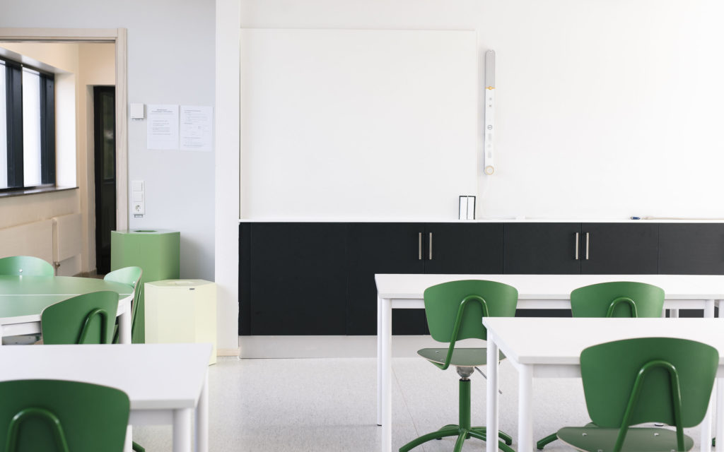 Vita bord och gröna stolar i klassrum